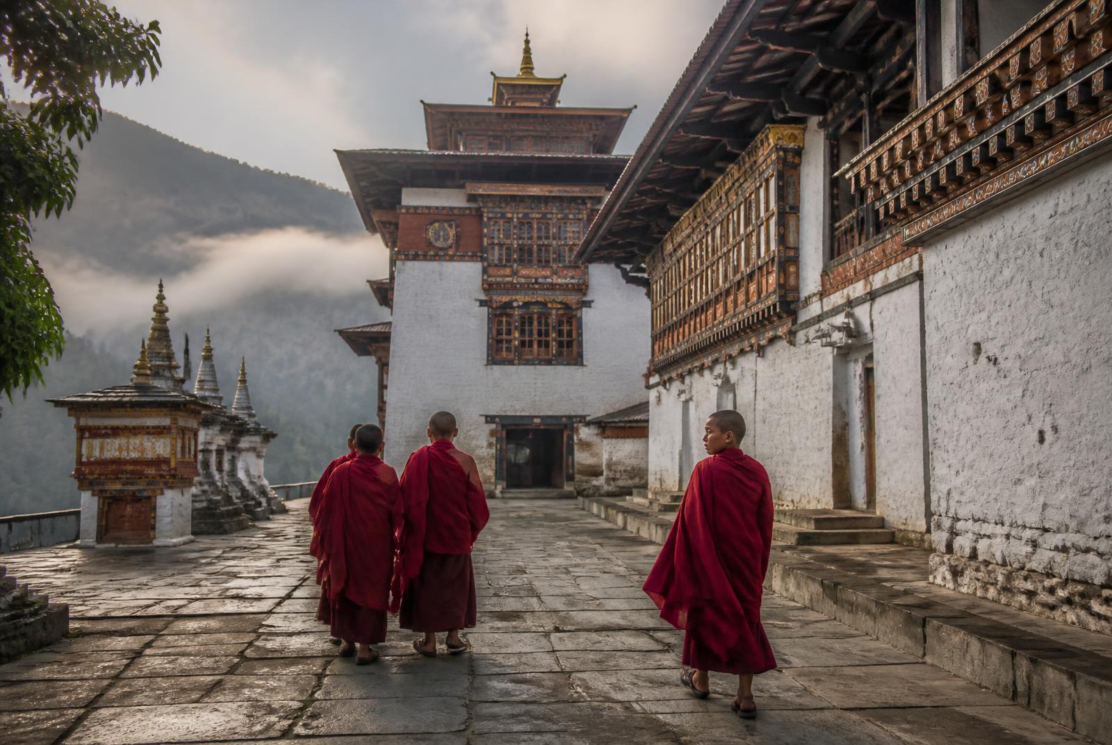 Monks walking through a Bhutanese monastery courtyard